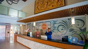 A hotel reception desk with a decorative wall mural, a large painting above, and a modern chandelier. - Bali Sun Tropical Hotel & Spa (Legian)