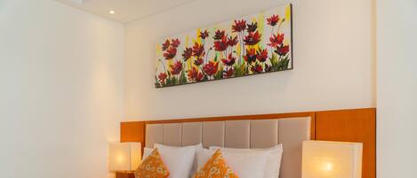 Habitación de hotel con una cama grande, dos mesitas de noche, un cuadro de flores y un teléfono en la mesita.