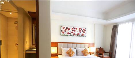 A hotel room with a large bed, a nightstand, a bedside table, a shower area, and a bathroom.
