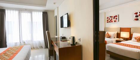 A hotel room with two beds, a desk, a chair, a television, and artwork on the walls.