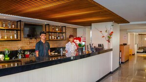 A modern bar area with a wooden ceiling, a flat-screen TV mounted on the wall, and a variety of bottles on shelves. - Bali Sun Tropical Hotel & Spa (Legian)