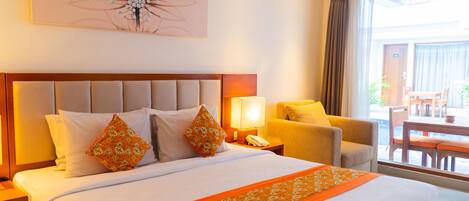 Habitación de hotel con una cama grande, una mesita de noche, una silla, una mesa y vistas al exterior.
