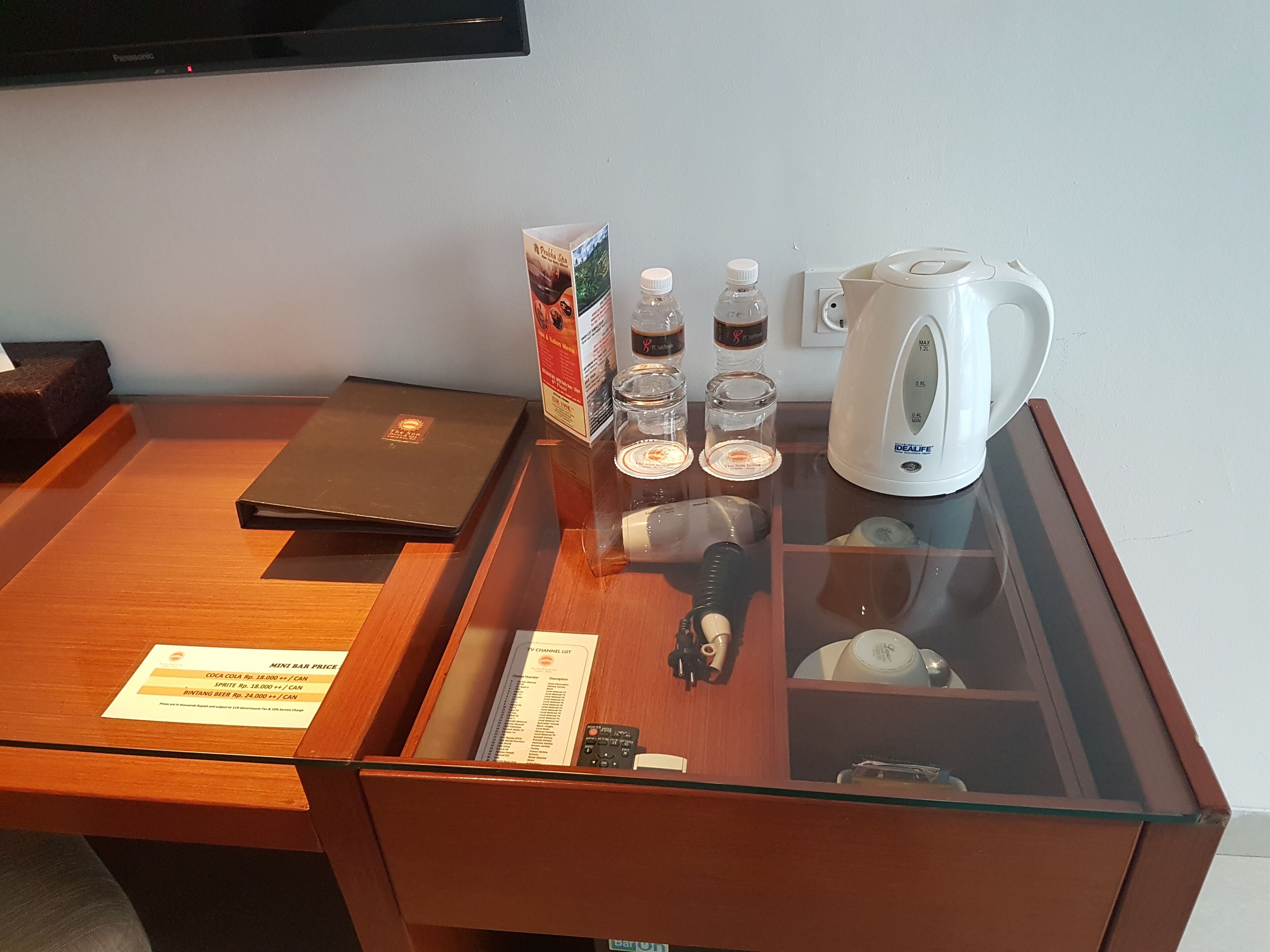 Egy szállodai szobában található íróasztal, rajta egy laptop, egy kávéfőző és egy minibar.