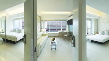 A modern hotel room with two beds, a desk, a chair, and a small table with fruit.