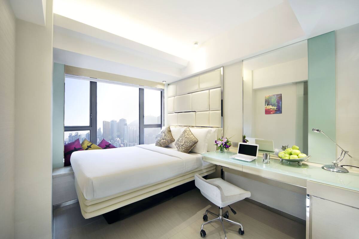 Una habitación de hotel moderna con cama, escritorio y vistas a la ciudad.