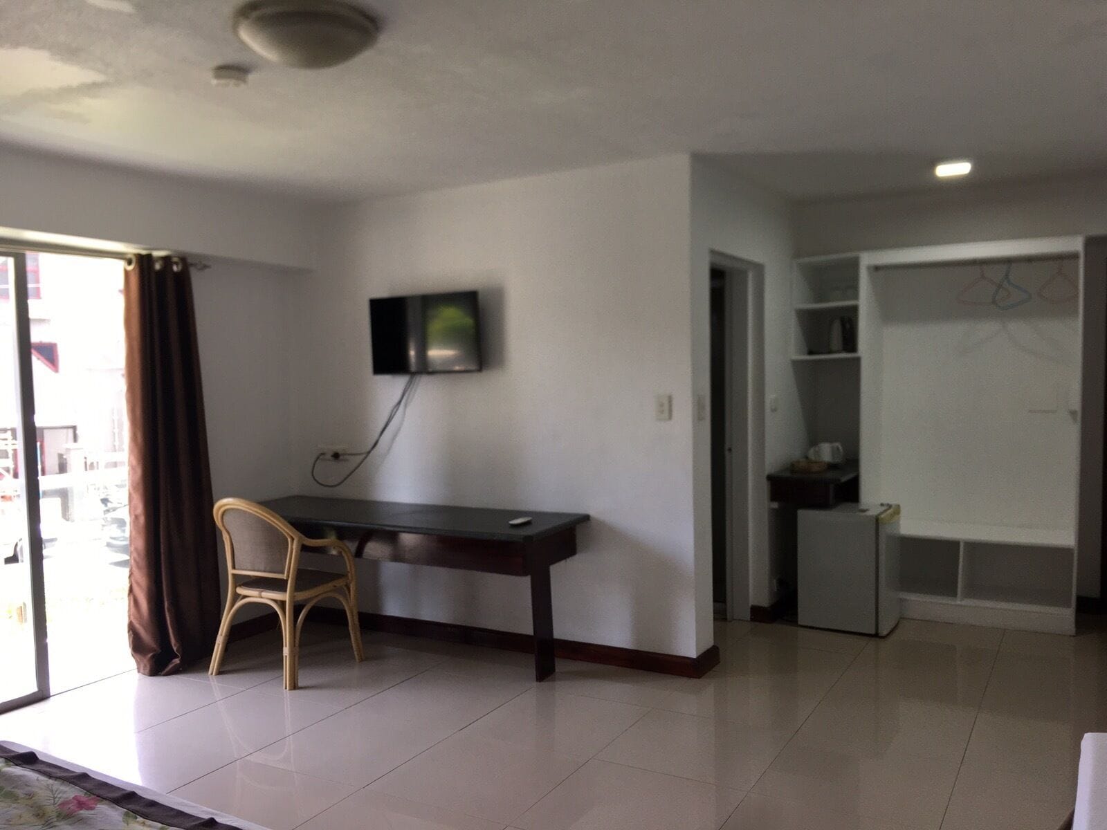 Una habitación con escritorio, silla y televisor montado en la pared.