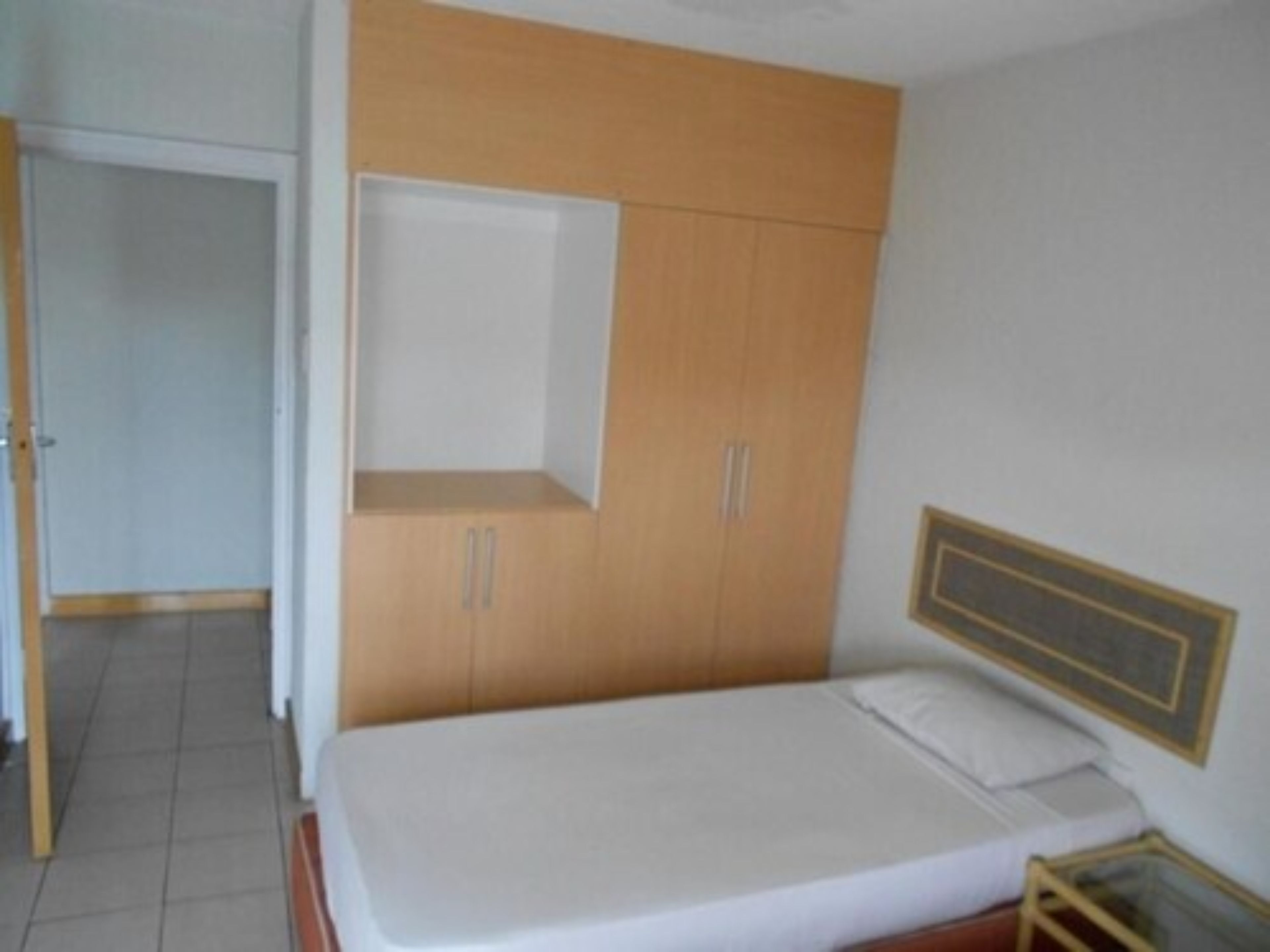 A bedroom with a bed, a wardrobe, and a small table.