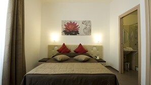 Ein Hotelzimmer mit Bett, zwei Nachttischen, einem Wandbild und einer Badezimmertür.