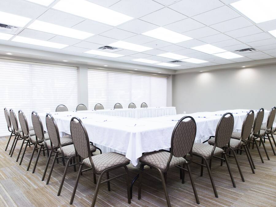 Une salle de conférence avec une longue table, des chaises et un plafond doté de luminaires carrés.