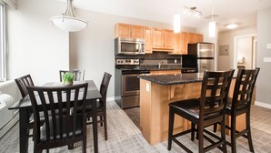 Una cocina moderna con armarios de madera, electrodomésticos de acero inoxidable y una isla central con taburetes de bar.