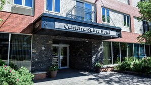 Entrada de un hotel con fachada de piedra, ventanas grandes y un letrero que dice 'Canterra Suites Hotel'.