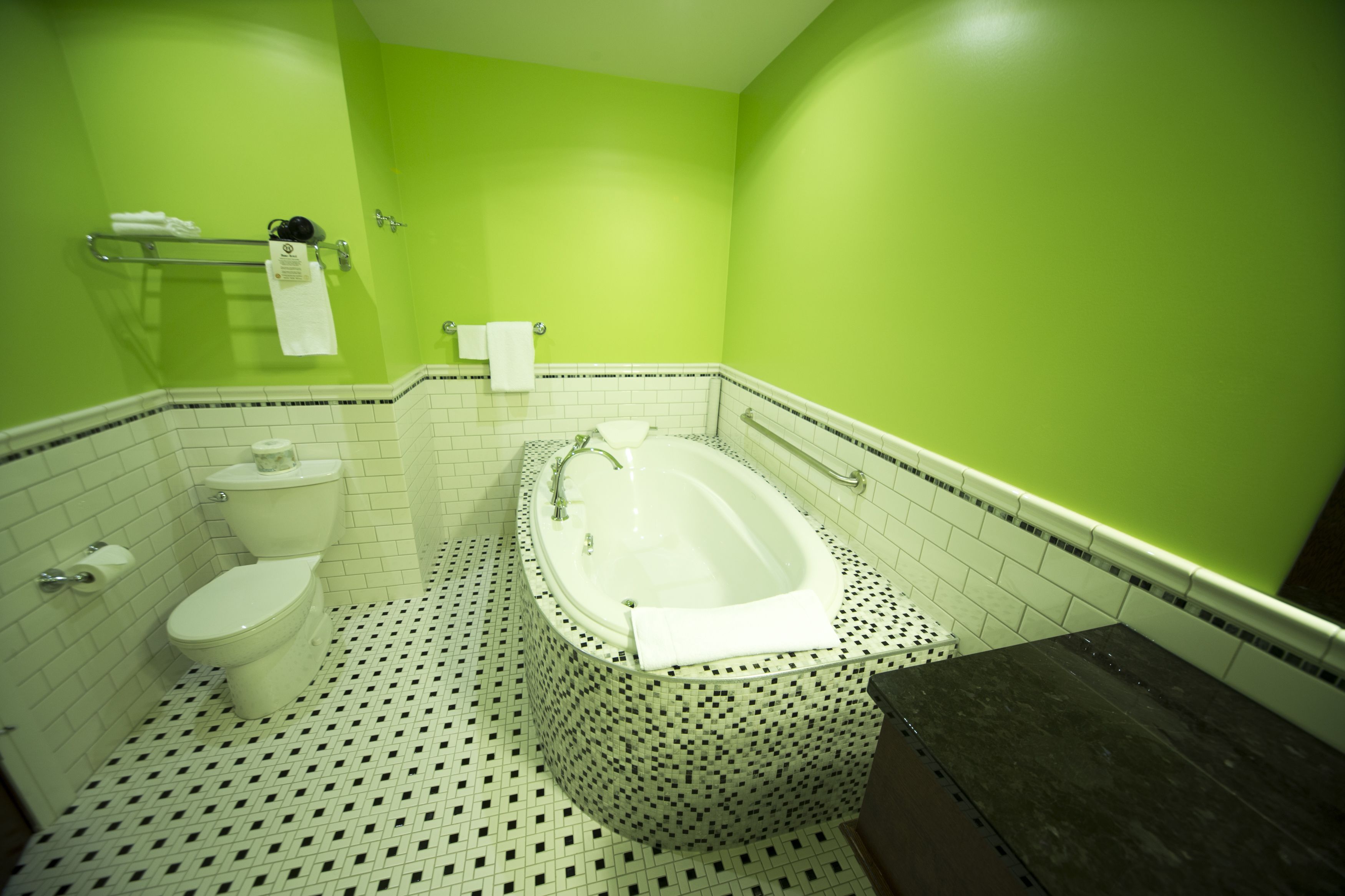 A bathroom with a white toilet, a white bathtub, and a green wall.