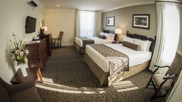 A hotel room with two beds, a desk, a chair, a TV, and a window with curtains.