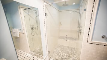 A modern bathroom with a glass-enclosed shower, white tiled walls, and a patterned floor.