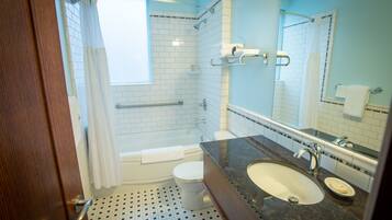 A bathroom with a bathtub, toilet, sink, and a mirror.