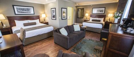 A hotel room with two beds, a sofa, a desk, and a dresser.