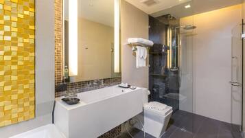 A modern bathroom with a large white sink, a glass-enclosed shower, and a tiled wall with a mosaic pattern.