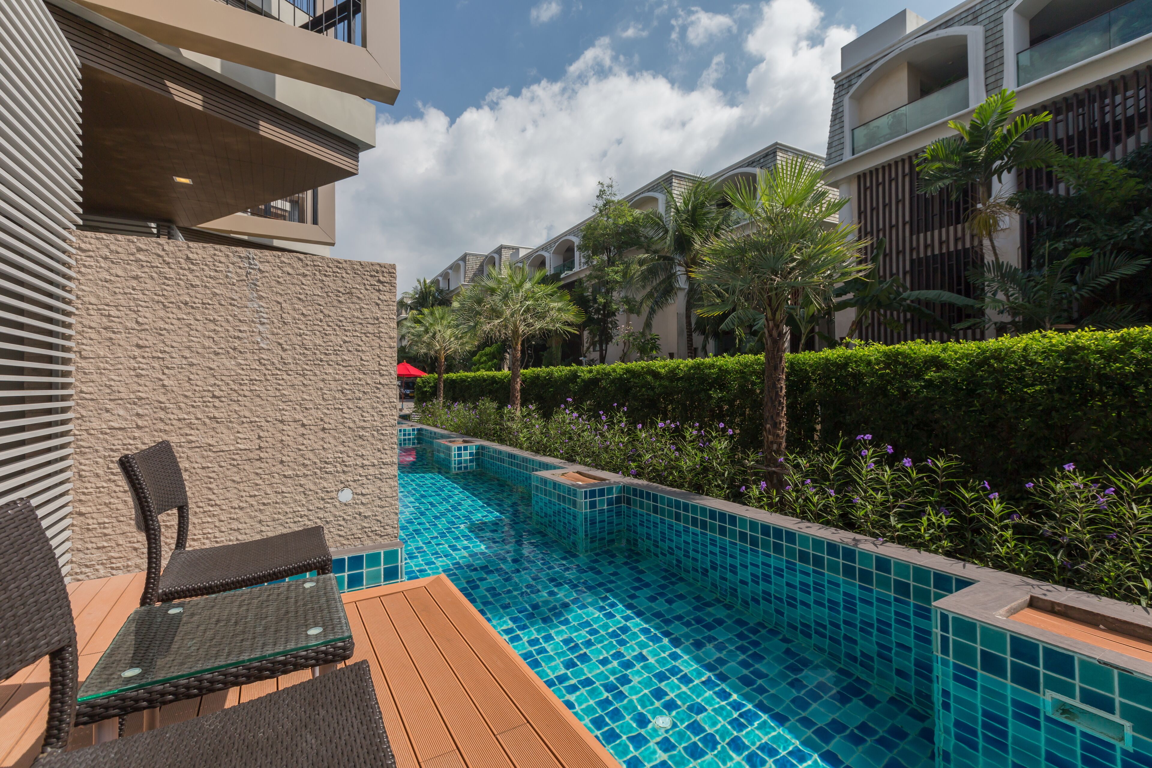 A modern hotel with a swimming pool, outdoor seating, and lush greenery.