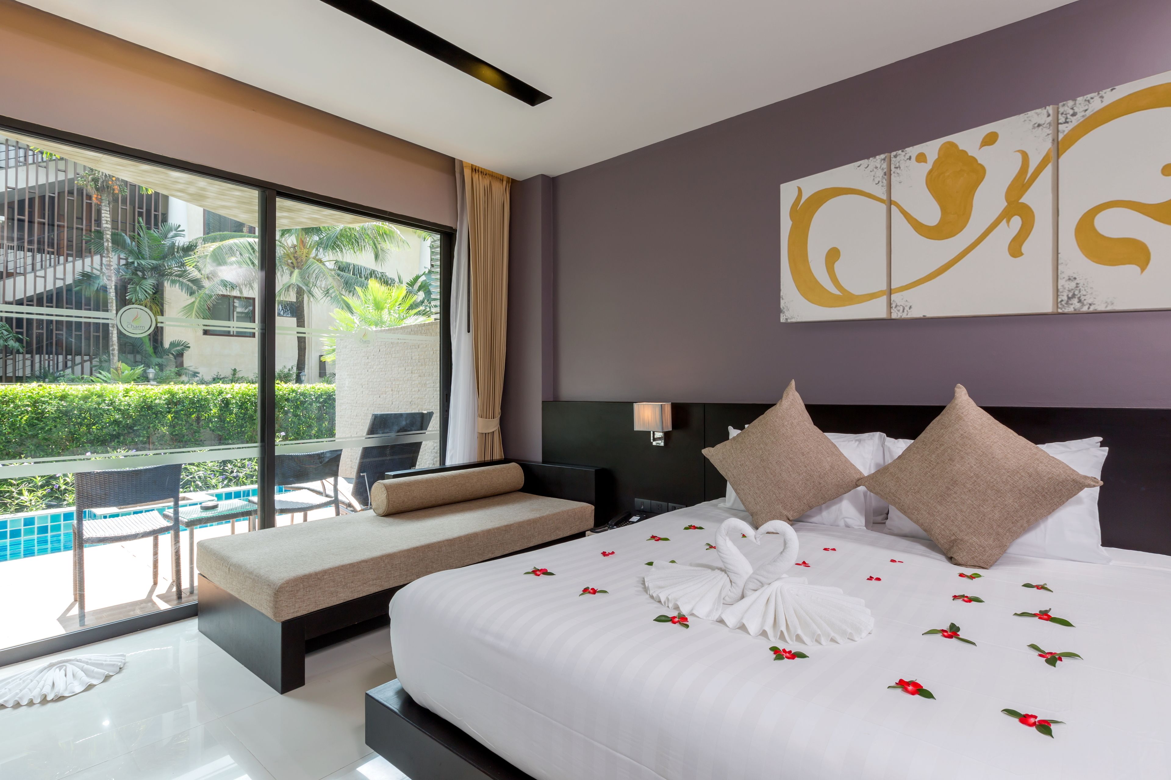 A modern hotel room with a large bed, a balcony with a pool view, and a decorative wall piece.