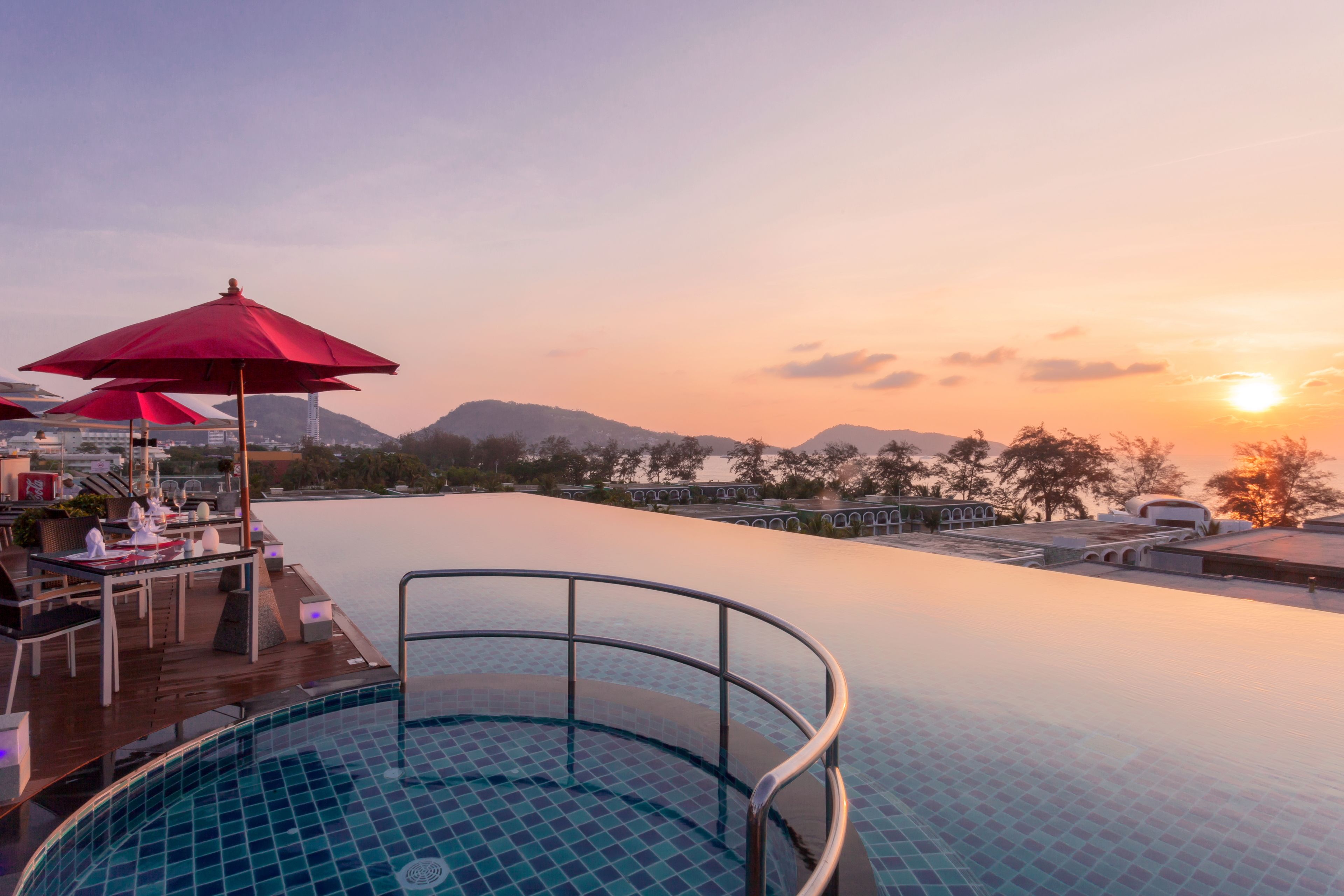 Una piscina infinita con vistas a la puesta de sol y montañas.