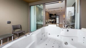 Un baño moderno con una bañera grande, un box de ducha de vidrio y una zona de estar con una silla y una mesita.
