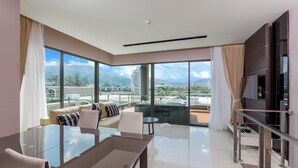 Una habitación de hotel moderna con un balcón grande, una zona de comedor y vistas a la ciudad.