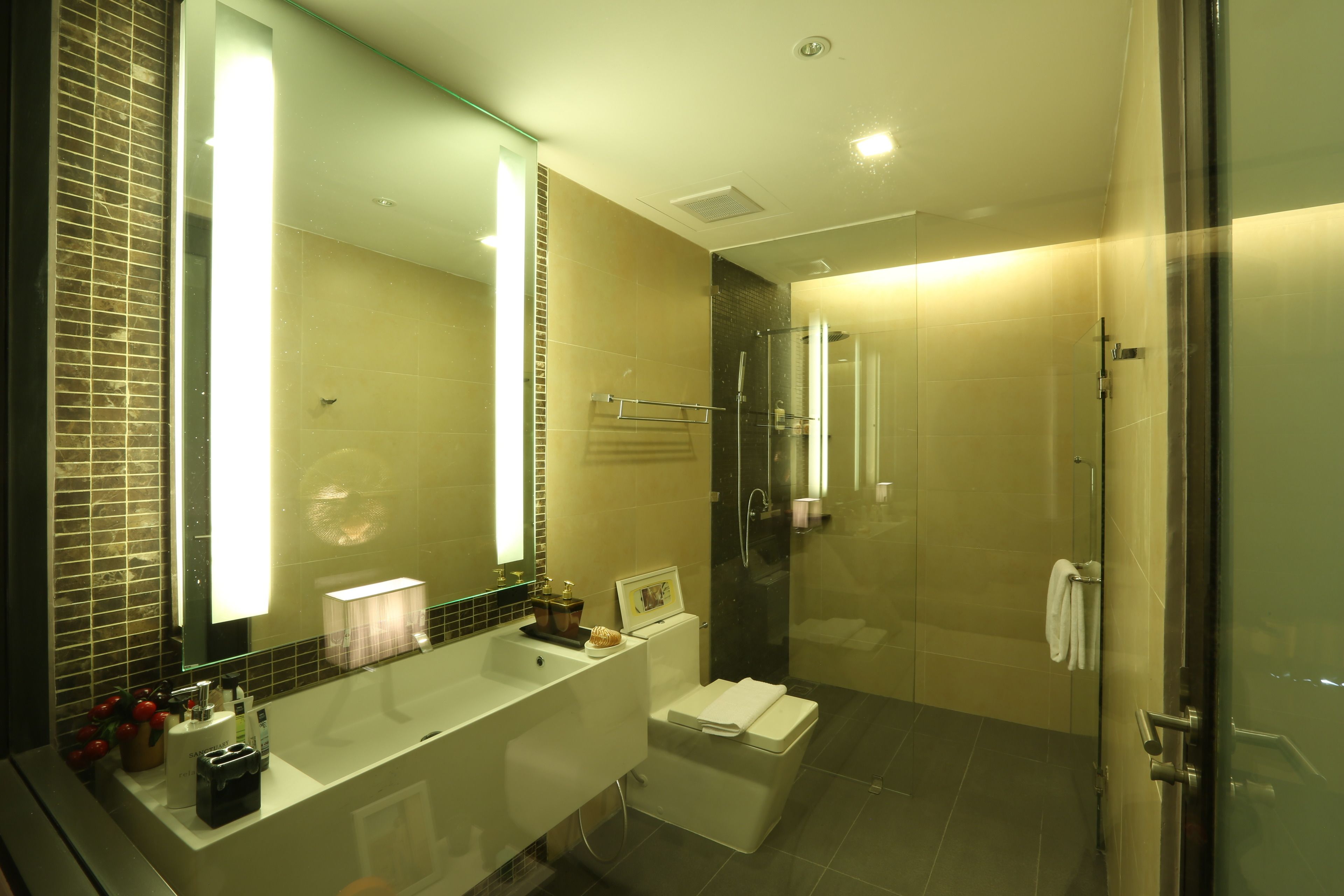 A modern bathroom with a large mirror, a bathtub, a toilet, and a shower area.