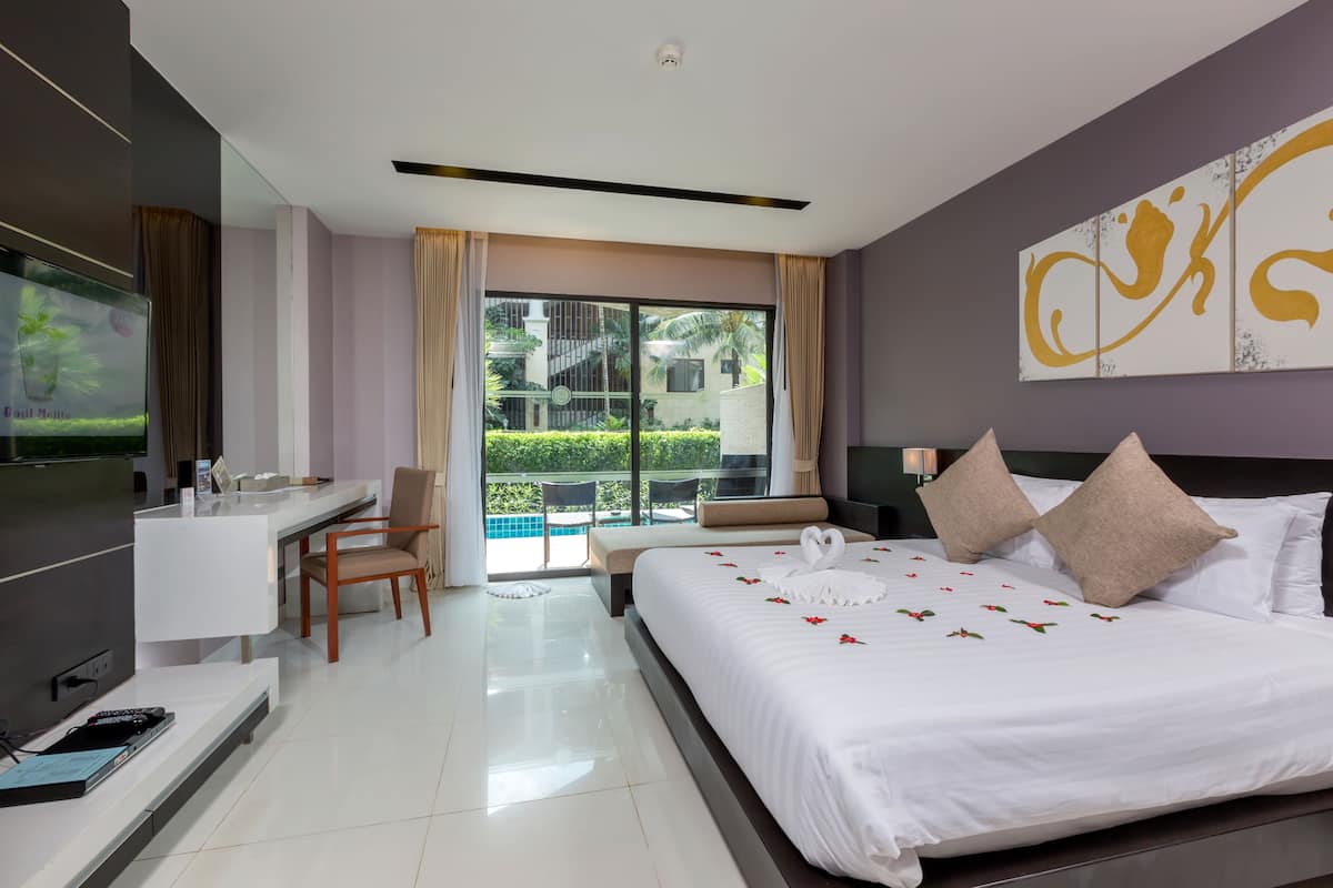 A modern hotel room with a large bed, a desk, and a view of a swimming pool.