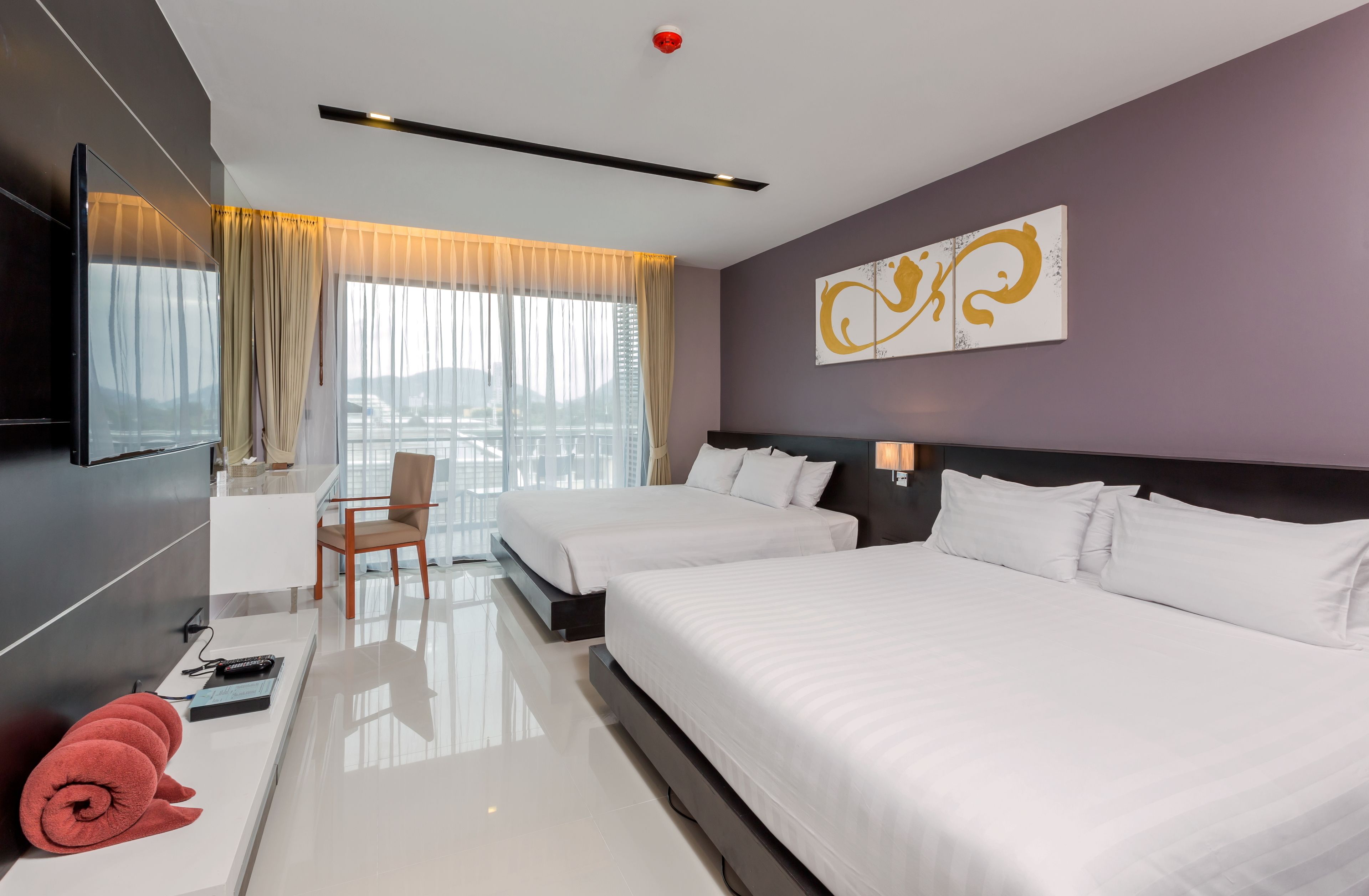 A modern hotel room with two beds, a desk, and a TV.