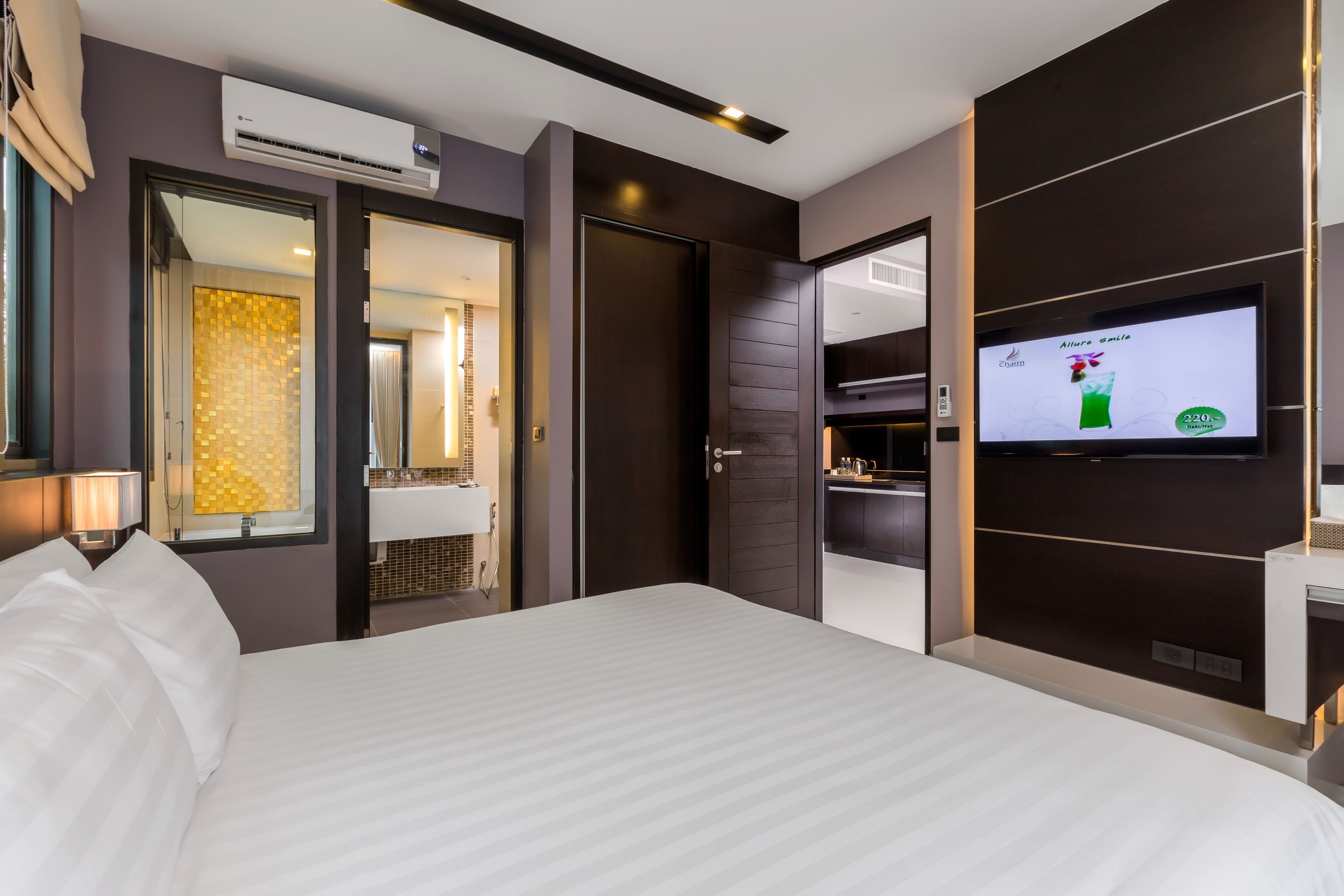 Ein modernes Hotelzimmer mit einem großen Bett, einem Fernseher und einem durchgegangenes Badezimmer.
