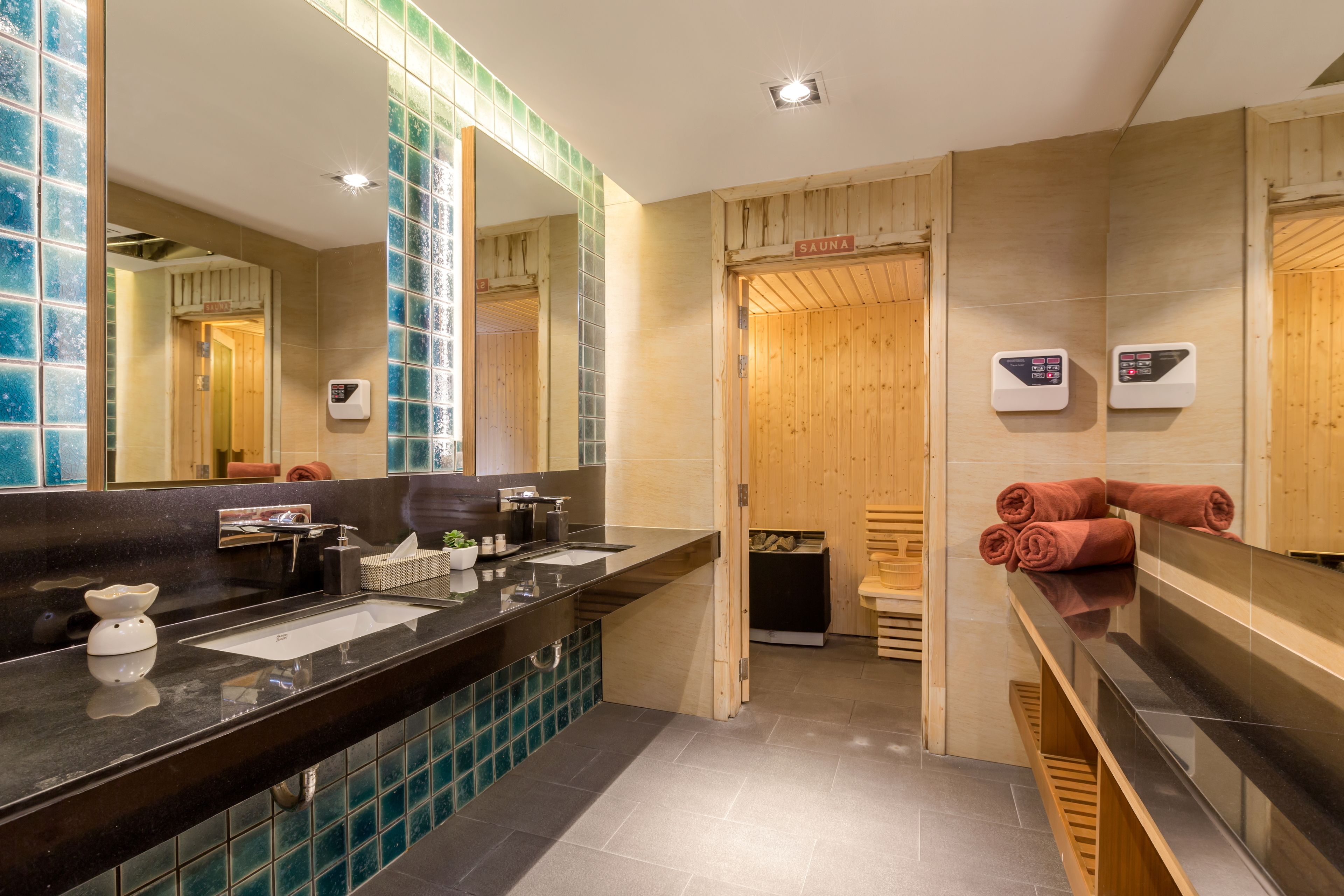 A modern bathroom with a black countertop, a large mirror, and a sauna sign.
