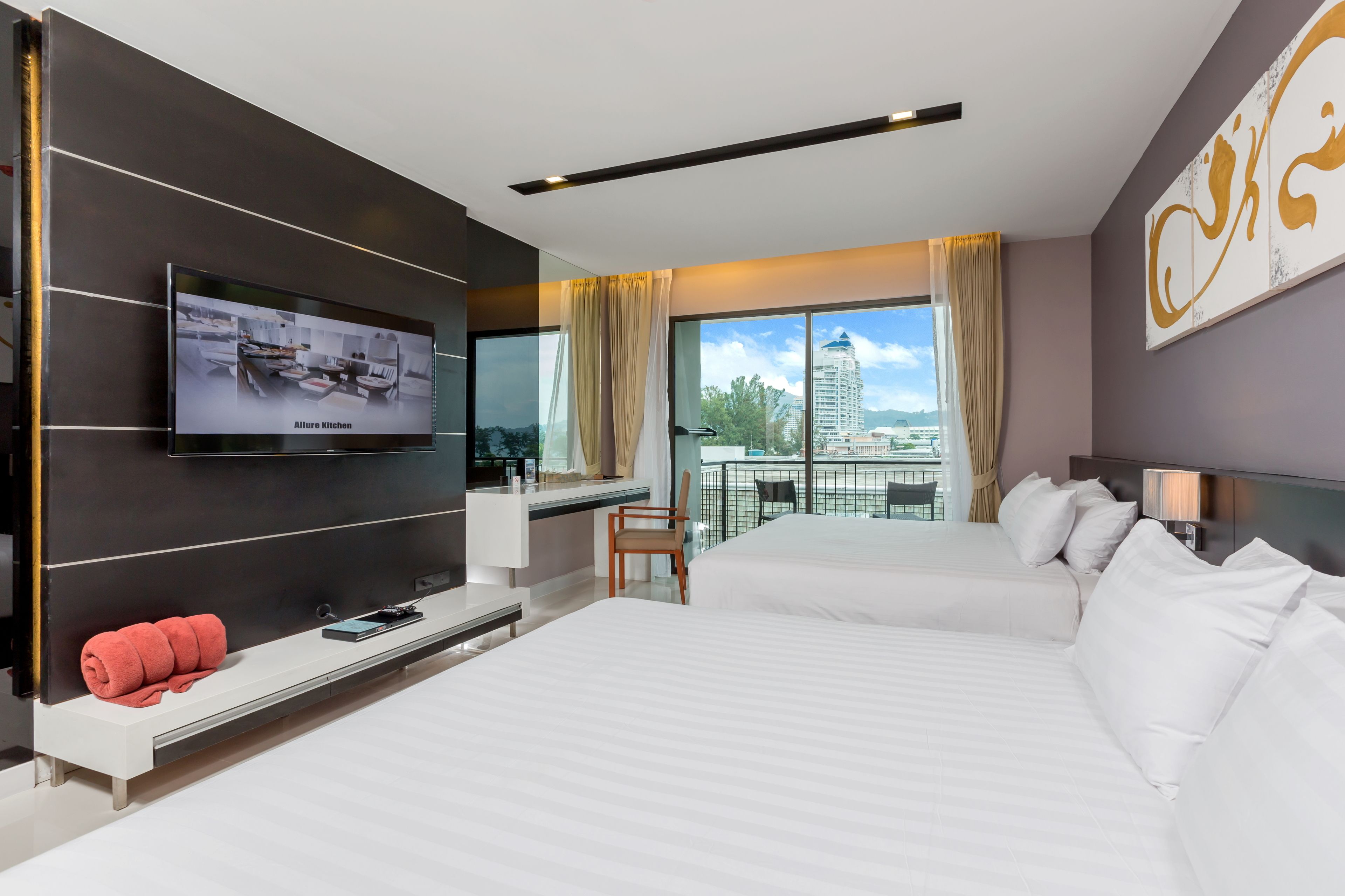 Una habitación de hotel moderna con una cama grande, un escritorio, un televisor montado en la pared y un balcón con vistas a la ciudad.