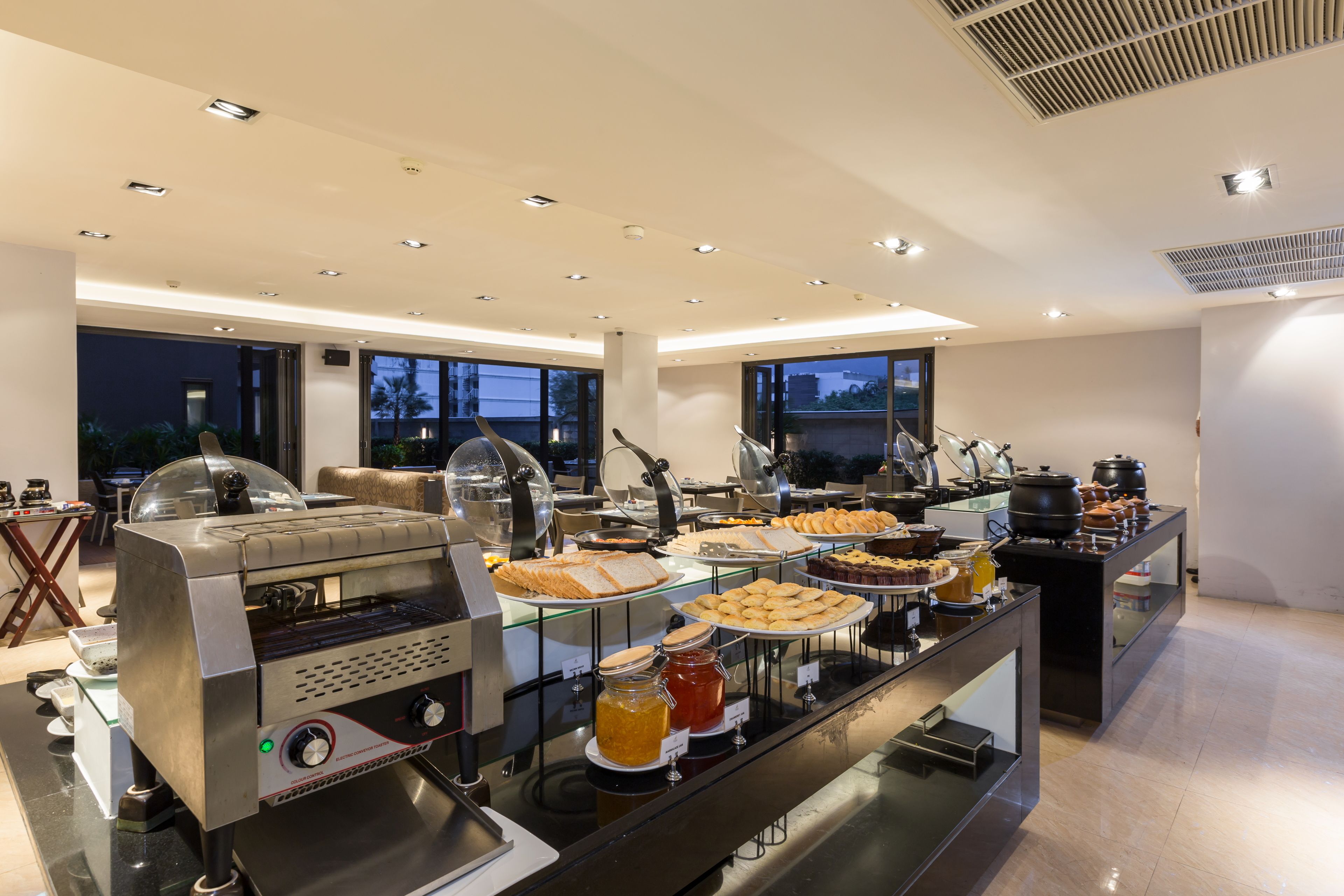 A buffet setup with a self-service grill, various food items, and condiments.