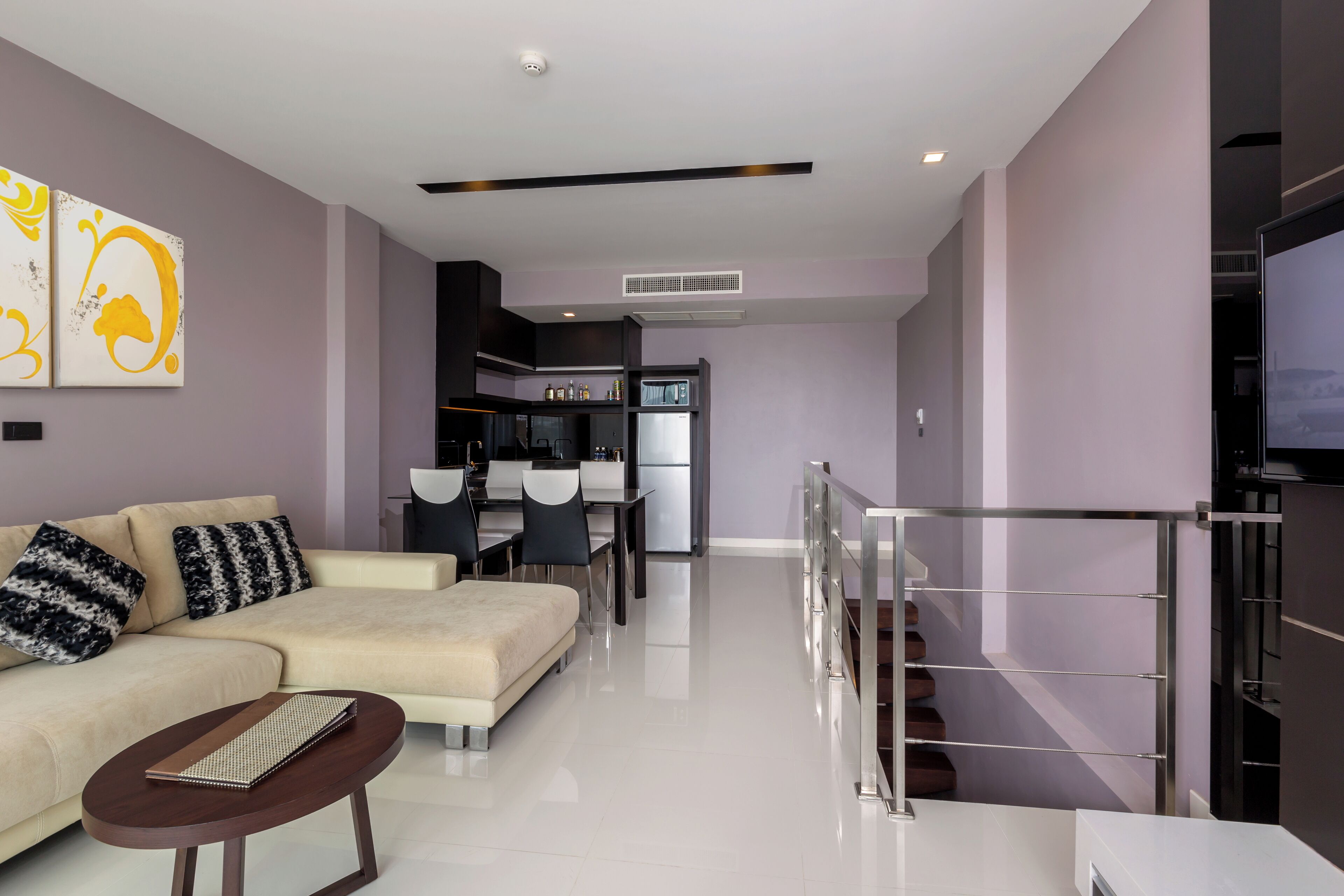 A modern living room with a sofa, coffee table, and a dining area with chairs.