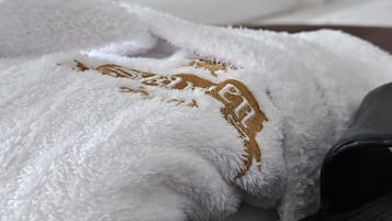 A neatly made bed with white and gold bedding, a black pillow, and a wooden headboard.