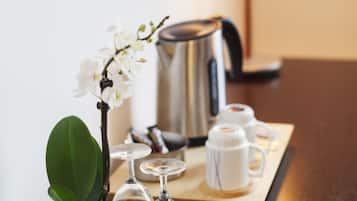 Una mesa ordenada con una orquídea en maceta, una cafetera y un juego de té.