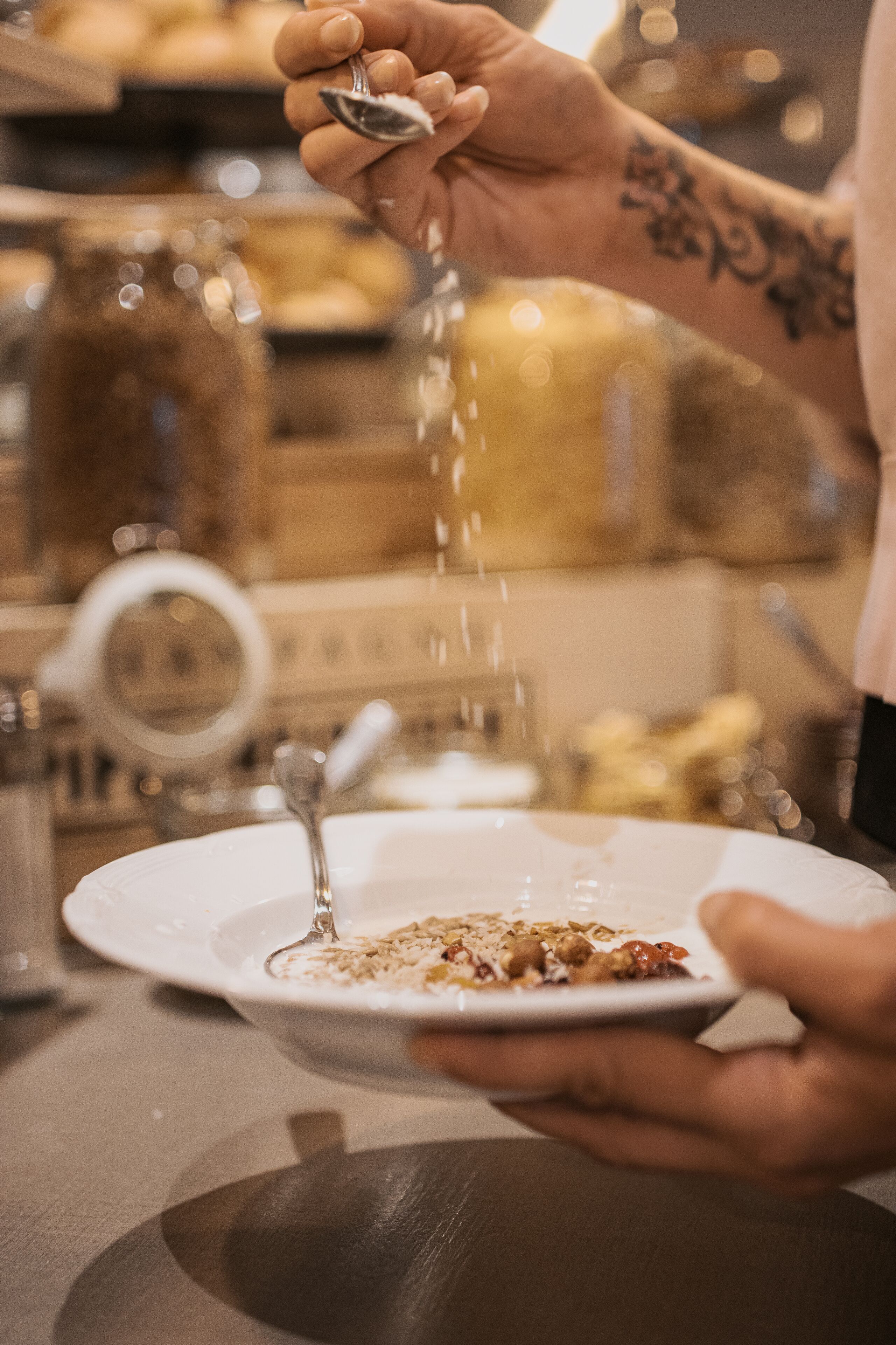 A person pouring a liquid from a spoon into a bowl on a plate.