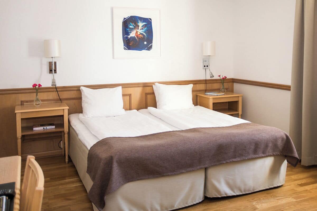 A hotel room with a double bed, two bedside tables, a desk, and a chair.