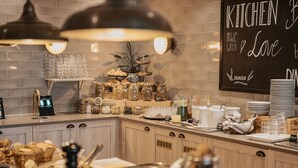 Disposición de un bufé con diferentes alimentos, un letrero que dice 'KITCHEN with Love' y el nombre de la marca 'SKANSEN'.