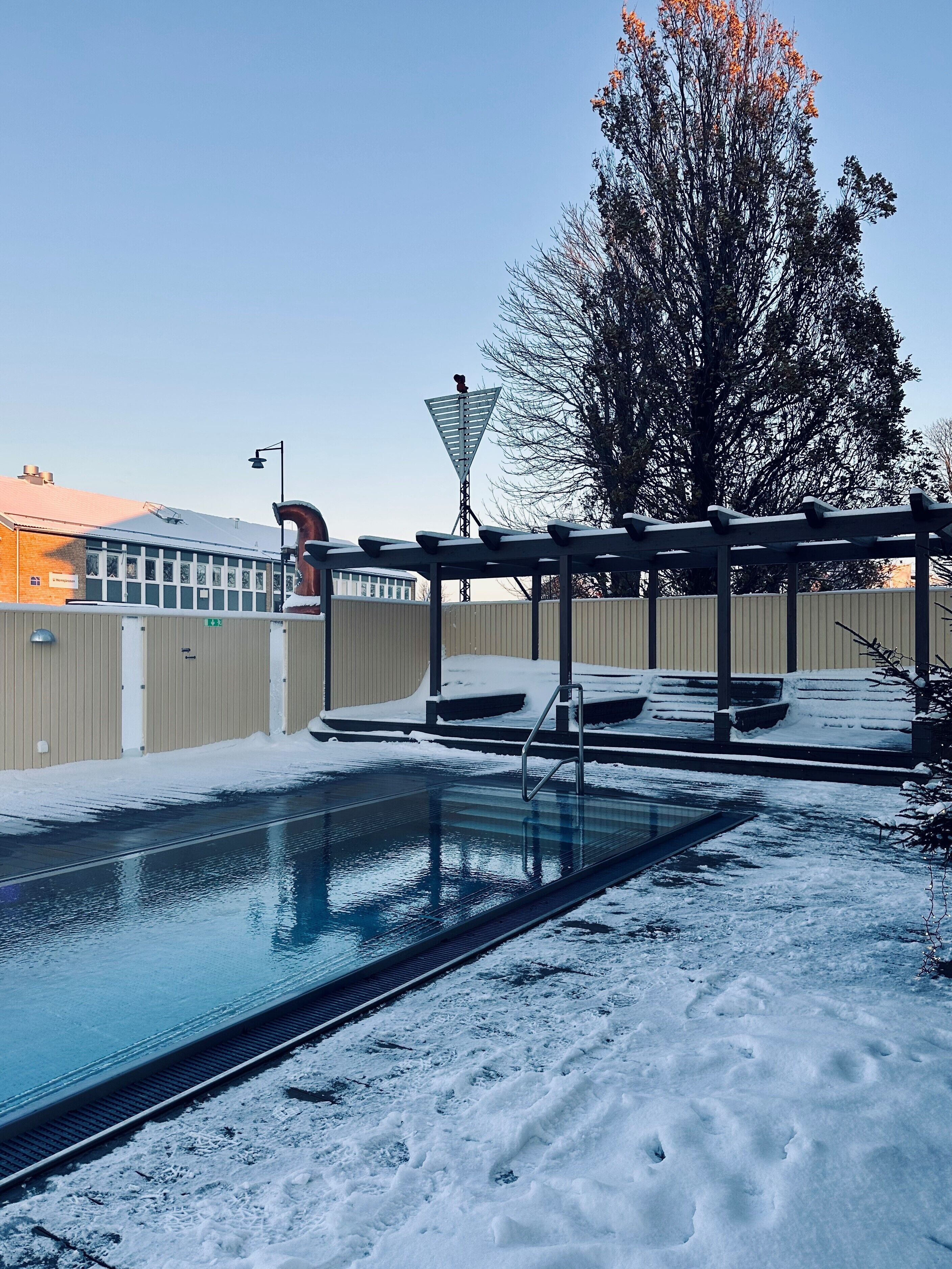 Ein Schwimmbecken mit überdachtem Bereich und Schnee auf dem Boden.