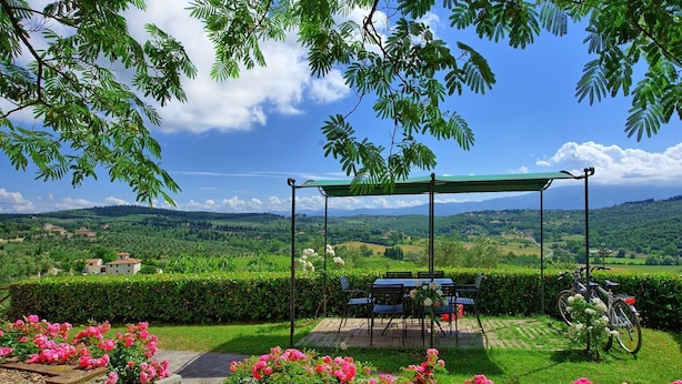 A patio with a swing set, a table with chairs, and a bicycle.