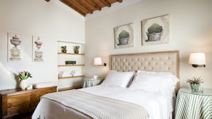 A bedroom with a large bed, a wooden headboard, bedside tables with lamps, and wall-mounted shelves with potted plants.