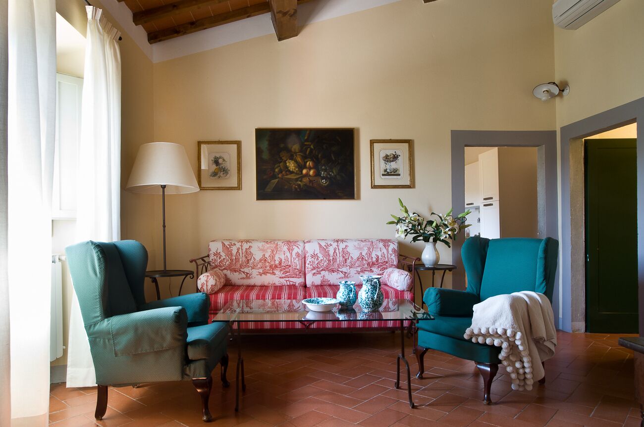 A living room with a sofa, two armchairs, a coffee table, and a painting on the wall.
