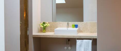 A modern bathroom with a skylight, a large mirror, a sink, and a shower.