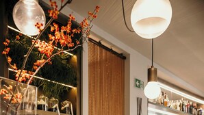 A bar area with a glass display case containing pastries and a decorative vase with red flowers. - Posta Design Hotel (Como)