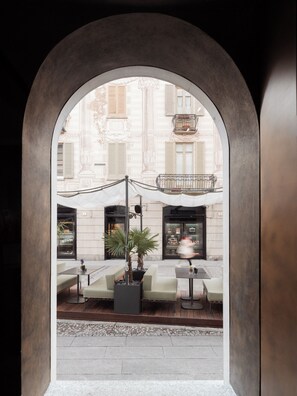 An outdoor seating area with tables and chairs, a potted plant, and a lamp. - Posta Design Hotel (Como)