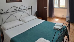 Une chambre à coucher avec un lit, un tableau, un climatiseur et une porte donnant sur un balcon.