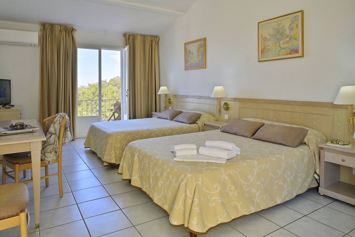 A hotel room with two beds, a desk, and a chair.