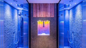 Une salle de bain moderne avec un mur en pierre, un panneau en bois au-dessus du lavabo et une zone de douche intégrée.
