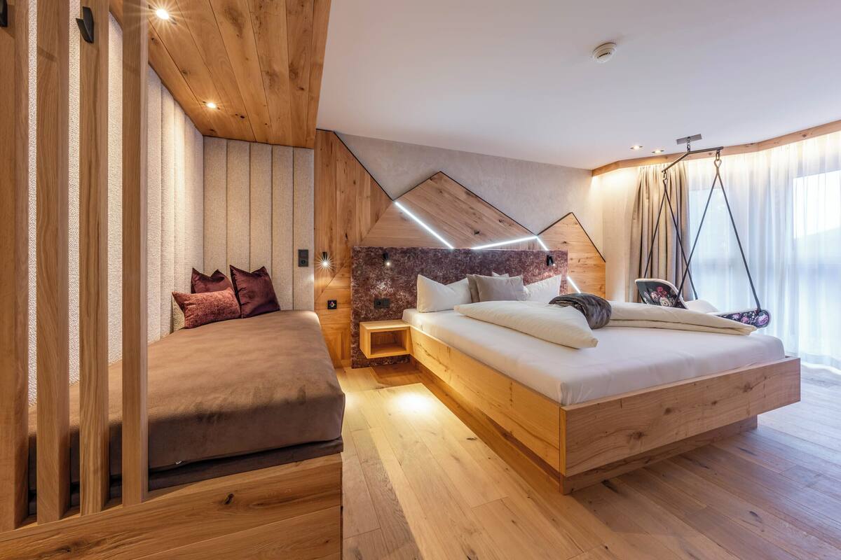 A modern bedroom with a wooden bed, a small sofa, and a hanging chair.